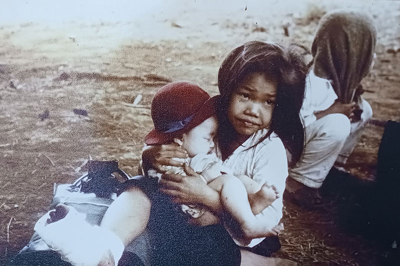 a little girl holding a younger sibling - image from vietnam war