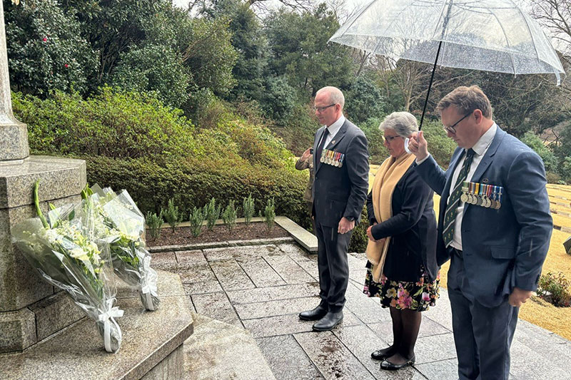 Major Trent Beilken (R) lays a wreath at Yokohama Cemetery