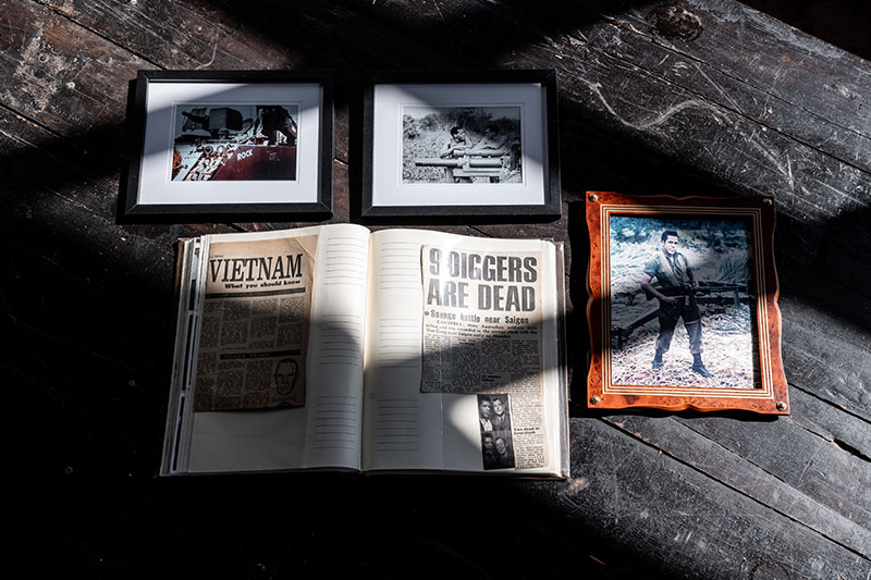 Framed images of Vietnam veteran John Burns with an open scrapbook with newspaper articles from the Vietman War. 