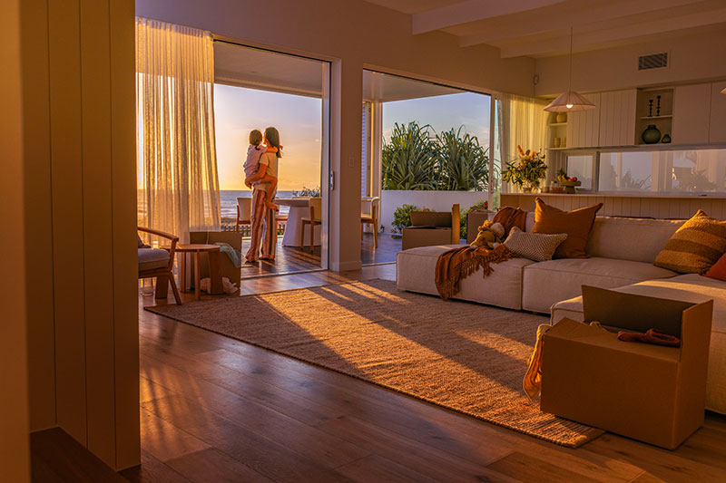 Mother and daughter standing outside a living room looking at the sunset.